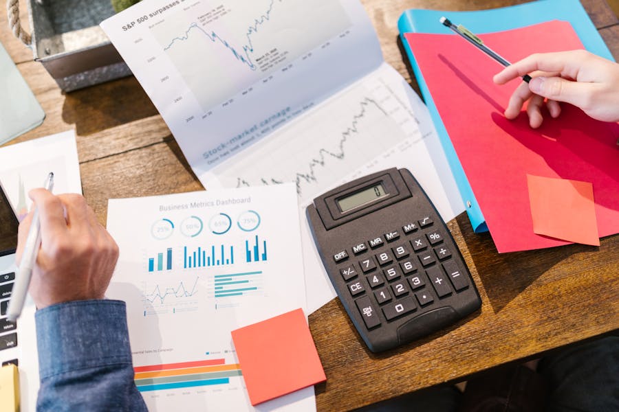 a brown desk with calculator and pieces of paper with charts