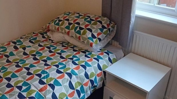 one of the houses bedrooms, a clean room with a bed with brightly coloured quilt cover, and a bedside table