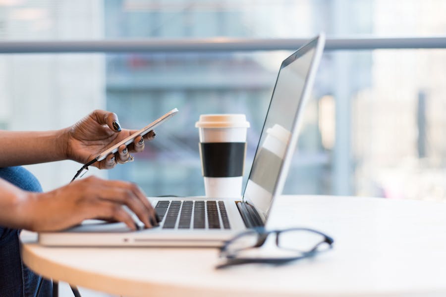 A woman is sitting at the table next to the window. She is using a laptop.