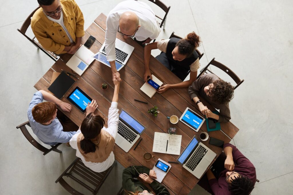 A group of people sitting round a table, each has their laptop open