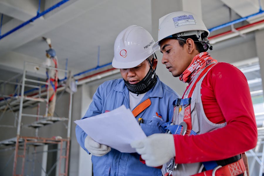 two men at a building site in hard caps and protective clothes are checking papers