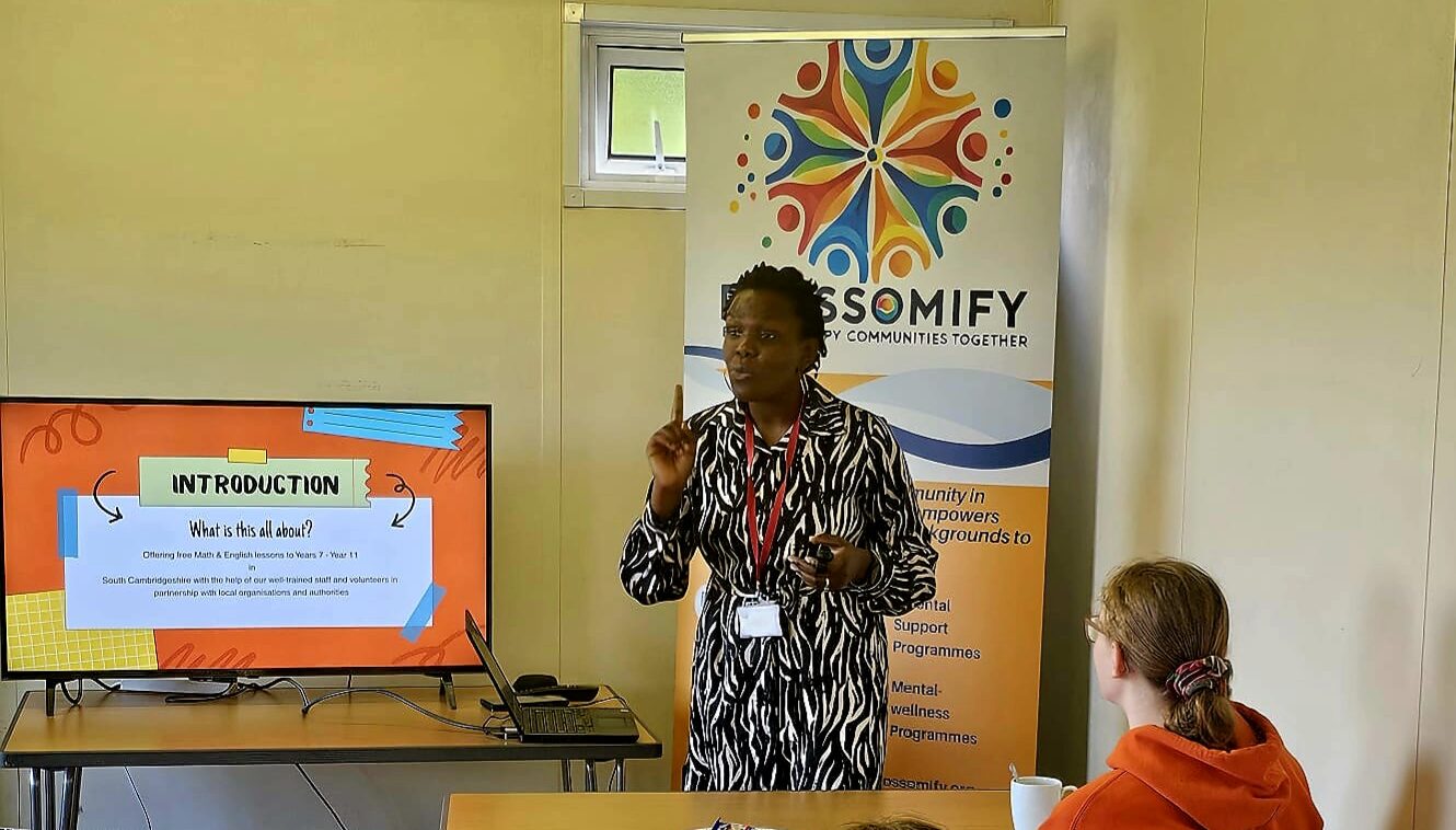 Blossomify volunteers standing at the front of a room, talking to pupils seated at tables.