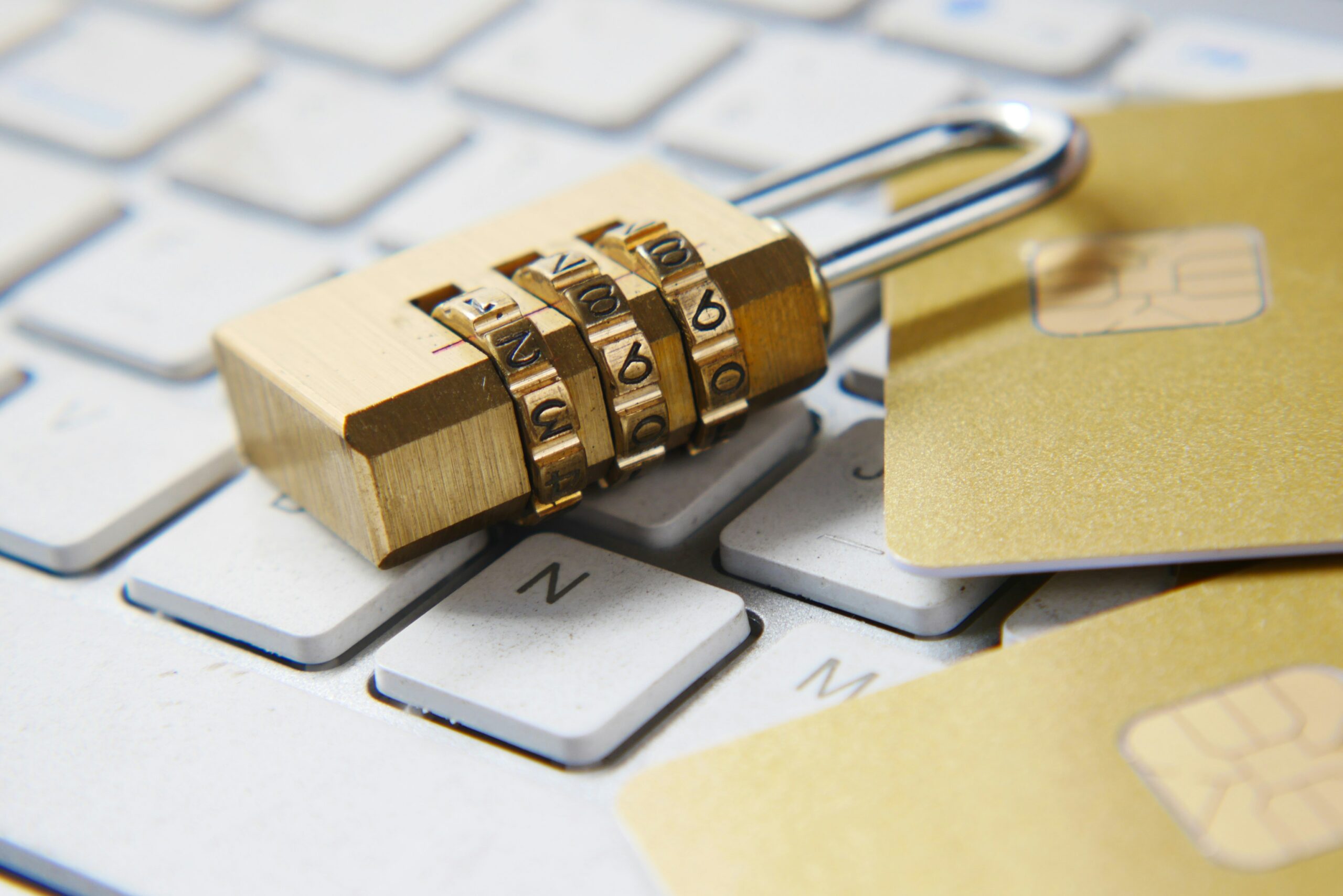 A gold combination padlock laying on top of a laptop keyboard