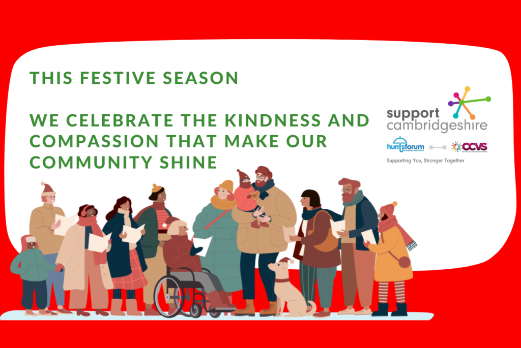 Christmas newsletter header with a red and white background. A cartoon illustration shows eleven people of varying ages and ethnicities, many wearing winter hats and scarves, caroling. The central message in green reads, "THIS CHRISTMAS WE CELEBRATE THE KINDNESS AND COMPASSION THAT MAKE OUR COMMUNITY SHINE." Logos for Support Cambridgeshire and partner organizations are in the top right corner.