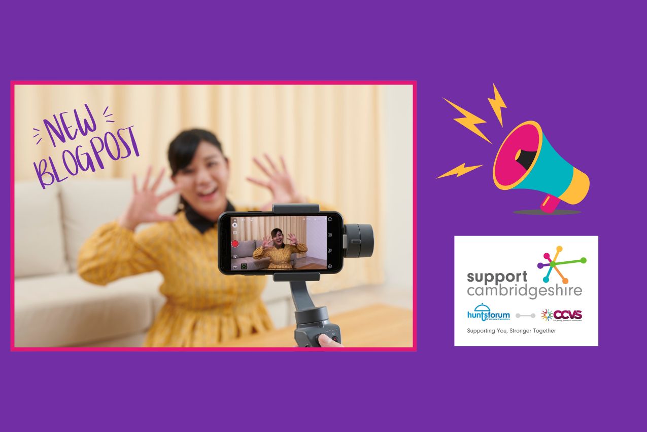 Purple background. We see a photo of someone wearing a yellow dress in front of a smart phone camera, they have their hands up waving and are smiling. We see the phone being held by a gimbal. We also see the Support Cambridgeshire interim logo and a graphic of a loud hailer. Text reads: Lights, Camera, Impact. How Charities Can Use Video and Storytelling to Connect and Inspire. New blogpost.